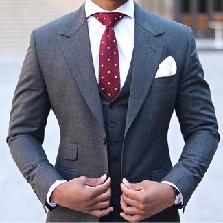 Come indossare e abbinare una cravatta a pois bordeaux per un uomo di 30 anni: Vestiti con un abito a tre pezzi grigio scuro e una cravatta a pois bordeaux per un look elegante e alla moda.