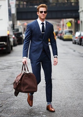Look alla moda per uomo: Abito blu scuro, Camicia elegante bianca, Scarpe oxford in pelle marroni, Borsone di tela marrone