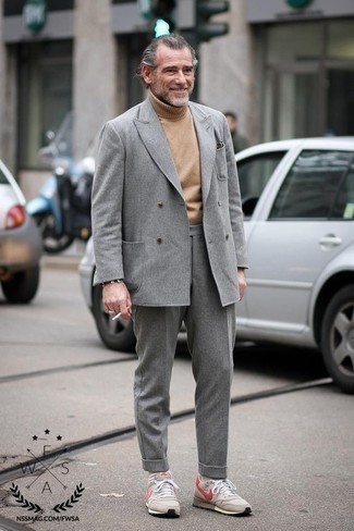 Come indossare e abbinare un abito grigio scuro per un uomo di 50 anni: Potresti indossare un abito grigio scuro e un dolcevita di lana marrone chiaro per un look elegante e alla moda. Per un look più rilassato, calza un paio di scarpe sportive beige.