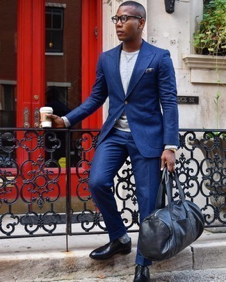 Moda uomo anni 20 in modo formale: Combina un abito blu scuro con una felpa grigia come un vero gentiluomo. Ti senti creativo? Completa il tuo outfit con un paio di scarpe derby in pelle nere.