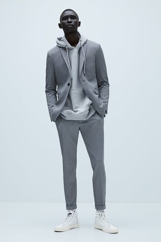 Come indossare e abbinare un abito grigio in modo smart-casual: Potresti combinare un abito grigio con una felpa con cappuccio grigia se preferisci uno stile ordinato e alla moda. Se non vuoi essere troppo formale, indossa un paio di sneakers alte di tela bianche.