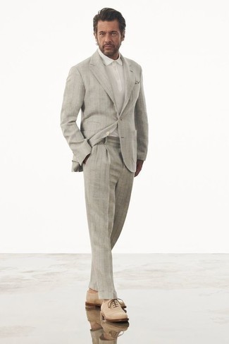 Moda uomo anni 40: Indossa un abito a righe verticali grigio e un polo bianco per un look elegante ma non troppo appariscente. Calza un paio di scarpe oxford in pelle scamosciata beige per dare un tocco classico al completo.