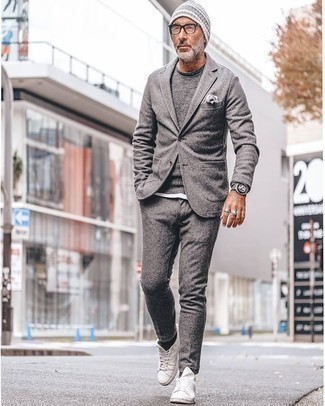 Quale abito indossare con un maglione girocollo grigio scuro per un uomo di 50 anni: Opta per un abito e un maglione girocollo grigio scuro per un look elegante e alla moda. Per un look più rilassato, prova con un paio di sneakers basse di tela bianche.