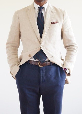 Come indossare e abbinare un blazer di cotone beige in modo formale: Scegli un blazer di cotone beige e pantaloni eleganti blu scuro per essere sofisticato e di classe.