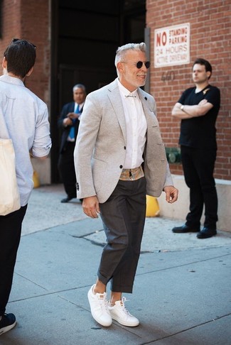 Come indossare e abbinare un blazer grigio con sneakers basse in pelle bianche per un uomo di 50 anni: Mostra il tuo stile in un blazer grigio con pantaloni eleganti neri come un vero gentiluomo. Abbina questi abiti a un paio di sneakers basse in pelle bianche.