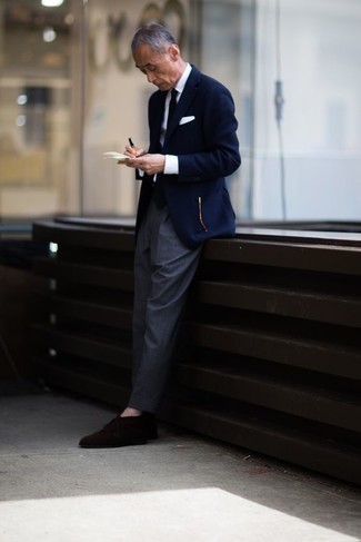 Come indossare e abbinare un blazer blu con pantaloni grigi per un uomo di 60 anni: Punta su un blazer blu e pantaloni grigi per essere sofisticato e di classe. Scegli uno stile classico per le calzature e scegli un paio di chukka in pelle scamosciata marrone scuro come calzature.