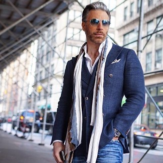 Come indossare e abbinare un blazer doppiopetto blu scuro e bianco per un uomo di 50 anni quando fa caldo in modo smart-casual: Prova a combinare un blazer doppiopetto blu scuro e bianco con jeans blu per un look da sfoggiare sul lavoro.