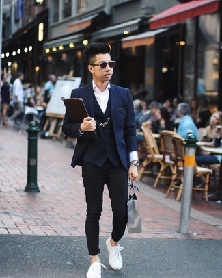 Come indossare e abbinare chino neri con sneakers basse di tela bianche in modo smart-casual: Opta per un blazer blu scuro e chino neri se preferisci uno stile ordinato e alla moda. Scegli uno stile casual per le calzature con un paio di sneakers basse di tela bianche.