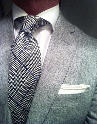 Come indossare e abbinare una cravatta bianca e blu scuro per un uomo di 30 anni: Abbina un blazer grigio con una cravatta bianca e blu scuro per essere sofisticato e di classe.