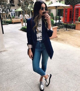 Look alla moda per donna: Blazer blu scuro, T-shirt girocollo stampata bianca e nera, Jeans aderenti blu, Scarpe derby in pelle argento