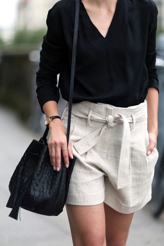 Come indossare e abbinare una borsa a secchiello in pelle per una donna di 30 anni quando fa molto caldo: Per un outfit della massima comodità, opta per una camicetta manica lunga nera e una borsa a secchiello in pelle.