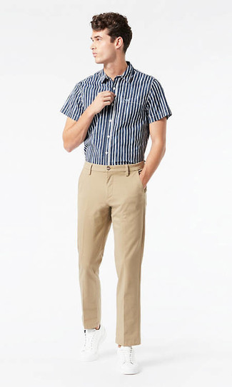 Look alla moda per uomo: Camicia a maniche corte a righe verticali blu scuro e bianca, Chino marrone chiaro, Sneakers basse di tela bianche