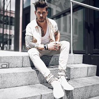 Come indossare e abbinare sneakers basse bianche: Indossa una camicia a maniche corte beige con jeans beige per un look semplice, da indossare ogni giorno. Sneakers basse bianche sono una valida scelta per completare il look.
