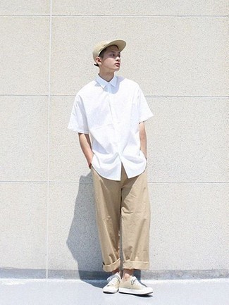Look alla moda per uomo: Camicia a maniche corte bianca, Chino marrone chiaro, Sneakers basse di tela beige, Berretto da baseball beige