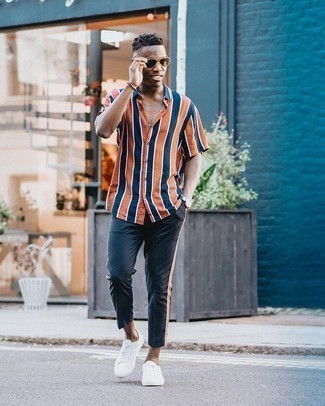 Look alla moda per uomo: Camicia a maniche corte a righe verticali arancione, Chino blu scuro, Sneakers basse di tela bianche, Occhiali da sole marroni