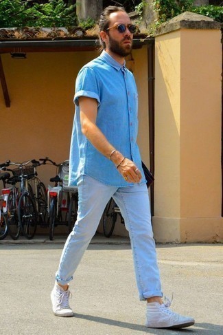 Look alla moda per uomo: Camicia a maniche corte in chambray azzurra, Jeans azzurri, Sneakers alte di tela bianche, Occhiali da sole blu scuro