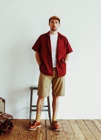 Trend da uomo 2022: Scegli una camicia a maniche corte a righe verticali rossa e pantaloncini marrone chiaro per un look semplice, da indossare ogni giorno. Scarpe derby in pelle terracotta daranno lucentezza a un look discreto.