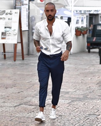 Look alla moda per uomo: Camicia a maniche lunghe bianca, Chino a righe verticali blu scuro, Sneakers basse bianche, Cintura in pelle blu scuro