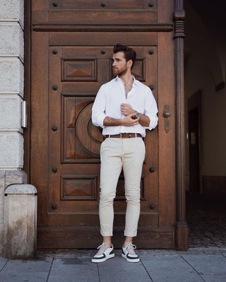 Look alla moda per uomo: Camicia a maniche lunghe bianca, Chino beige, Sneakers basse in pelle bianche e blu scuro, Cintura in pelle marrone