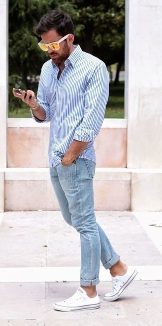 Look alla moda per uomo: Camicia a maniche lunghe a righe verticali bianca e blu, Jeans azzurri, Sneakers basse di tela bianche, Occhiali da sole senapi