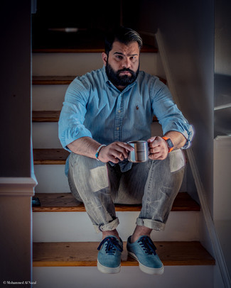 Look alla moda per uomo: Camicia a maniche lunghe in chambray azzurra, Jeans grigi, Sneakers basse di tela blu, Orologio di gomma arancione