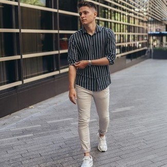 Look alla moda per uomo: Camicia a maniche lunghe a righe verticali nera e bianca, Jeans beige, Scarpe sportive bianche, Orologio argento