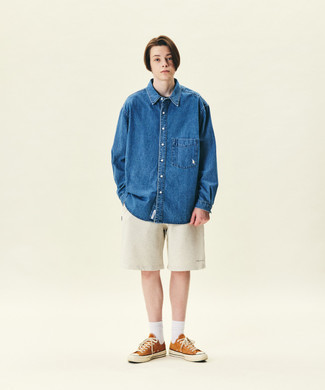 Look alla moda per uomo: Camicia di jeans blu, Pantaloncini sportivi beige, Sneakers basse di tela arancioni, Calzini bianchi