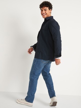 Come indossare e abbinare jeans blu con sneakers alte di tela bianche per un uomo di 20 anni: Indossa una camicia giacca blu scuro e jeans blu per un look raffinato per il tempo libero. Mettiti un paio di sneakers alte di tela bianche per un tocco più rilassato.