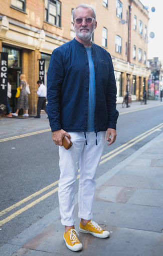 Come indossare e abbinare chino bianchi per un uomo di 60 anni: Vestiti con una camicia giacca blu scuro e chino bianchi per creare un look smart casual. Calza un paio di sneakers basse di tela senapi per un tocco più rilassato.