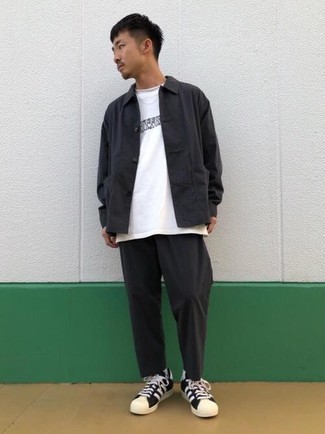 Look alla moda per uomo: Camicia giacca nera, T-shirt girocollo stampata bianca e nera, Chino neri, Sneakers basse di tela nere e bianche
