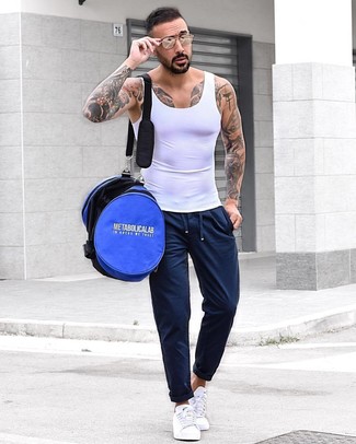 Look alla moda per uomo: Canotta bianca, Pantaloni sportivi blu scuro, Sneakers basse bianche, Borsa per lo sport blu