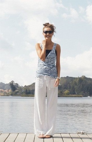 Look alla moda per donna: Canotta a righe orizzontali bianca e blu scuro,  Pantaloni larghi di lino bianchi, Infradito beige, Occhiali da sole neri