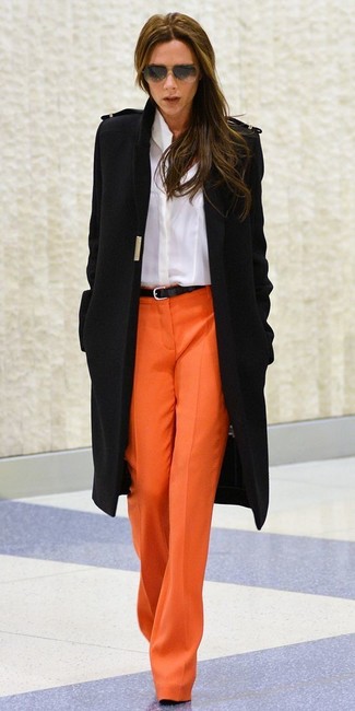 Moda donna anni 40: Punta su un cappotto nero e pantaloni larghi arancioni per un look semplice ed elegante.