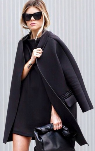 Come indossare e abbinare un vestito nero per una donna di 30 anni quando fa gelo: Combina un vestito nero con un cappotto nero per un look semplice ed elegante.