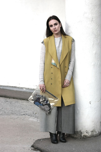 Look alla moda per donna: Cappotto senza maniche senape, Maglione girocollo grigio, Pantaloni larghi grigi, Stivaletti in pelle neri