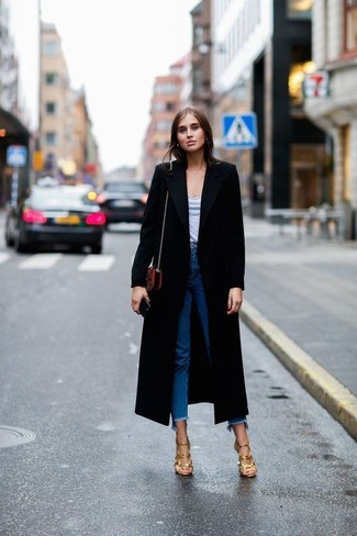 Come indossare e abbinare un cappotto nero per una donna di 30 anni: Indossa un cappotto nero e jeans con frange blu per un look semplice, da indossare ogni giorno. Sandali con tacco in pelle dorati sono una splendida scelta per completare il look.