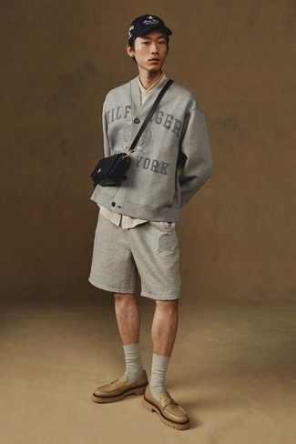 Moda uomo anni 20: Scegli un outfit rilassato in un cardigan ricamato grigio e pantaloncini sportivi grigi. Opta per un paio di mocassini eleganti in pelle marrone chiaro per dare un tocco classico al completo.