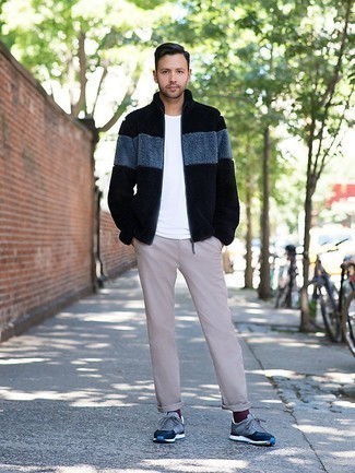Look alla moda per uomo: Cardigan con zip di pile nero, T-shirt girocollo bianca, Chino beige, Scarpe sportive blu