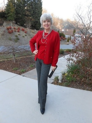 Moda donna anni 50: Indossa un cardigan rosso con pantaloni eleganti grigio scuro per un look davvero alla moda. Stivaletti in pelle neri sono una eccellente scelta per completare il look.