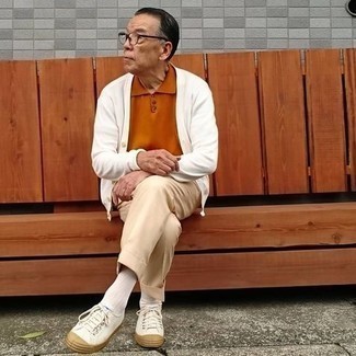 Moda uomo anni 60 quando fa caldo: Vestiti con un cardigan bianco e pantaloni eleganti beige come un vero gentiluomo. Per distinguerti dagli altri, scegli un paio di sneakers basse di tela bianche come calzature.