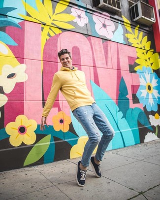 Come indossare e abbinare un maglione giallo per un uomo di 30 anni: Vestiti con un maglione giallo e jeans aderenti strappati azzurri per un'atmosfera casual-cool. Sfodera il gusto per le calzature di lusso e mettiti un paio di sneakers basse di tela blu scuro.