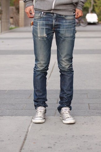 Look alla moda per uomo: Felpa con cappuccio grigia, Jeans blu scuro, Sneakers basse di tela grigie