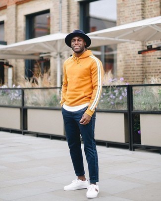 Look alla moda per uomo: Felpa con cappuccio arancione, T-shirt girocollo bianca, Chino blu scuro, Sneakers basse di tela stampate bianche