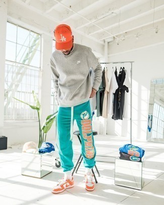 Look alla moda per uomo: Felpa grigia, Pantaloni sportivi stampati acqua, Sneakers basse in pelle arancioni, Berretto da baseball arancione