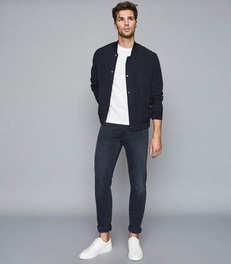 Come indossare e abbinare una giacca college nera con jeans blu scuro: Metti una giacca college nera e jeans blu scuro per affrontare con facilità la tua giornata. Sneakers basse di tela bianche sono una buona scelta per completare il look.
