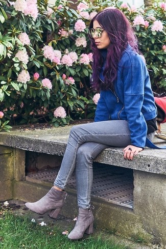 Look alla moda per donna: Giacca da moto in pelle scamosciata blu, Jeans aderenti grigi, Stivaletti in pelle scamosciata grigi, Occhiali da sole dorati