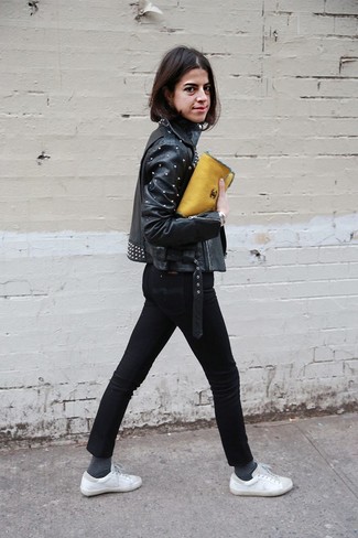 Look alla moda per donna: Giacca da moto in pelle con borchie nera, Dolcevita nero, Jeans aderenti neri, Sneakers basse bianche