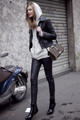Look alla moda per donna: Giacca da moto in pelle nera, Felpa con cappuccio grigia, Jeans aderenti in pelle neri, Stivaletti in pelle neri