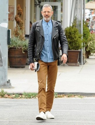 Look di Jeff Goldblum: Giacca da moto in pelle nera, Camicia a maniche lunghe in chambray azzurra, Chino marroni, Sneakers basse di tela bianche