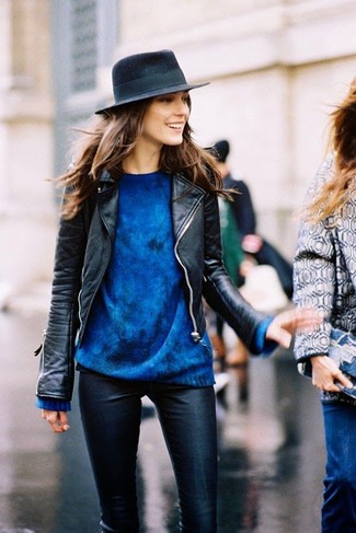 Look alla moda per donna: Giacca da moto in pelle nera, Maglione oversize blu, Pantaloni skinny in pelle neri, Borsalino di lana blu scuro